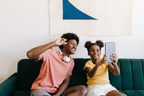 Siblings taking selfie at home with a digital tablet