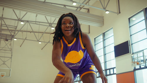 Young woman dribbling basketball in gym