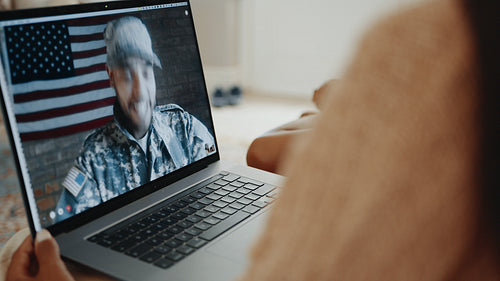 Military family video chatting with deployed dad using a laptop