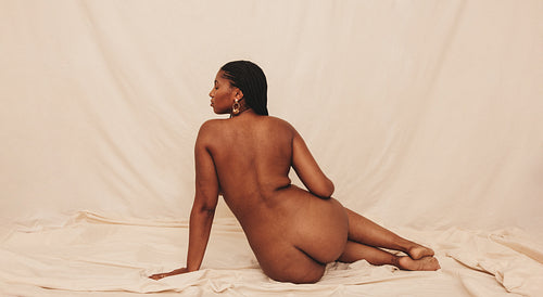 Rearview of a naked woman sitting in a studio