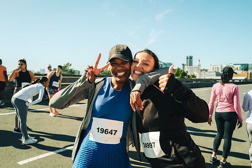 Joyful female friends smiling before a half marathon race