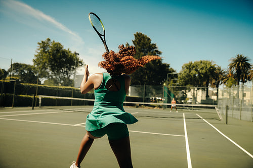 Female tennis player hitting a hard backhand shot during an intense outdoor rally