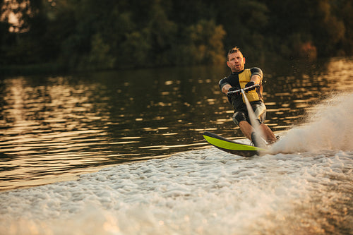 Man riding wakeboard on wave of motorboat