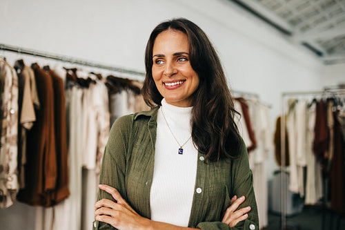 Female shop owner standing with crossed arms in her clothing store