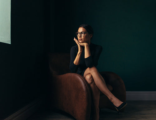 Beautiful young woman sitting on chair and looking away