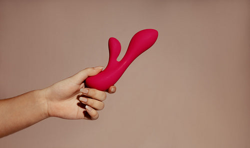 Feminine pleasure: Woman holding a dual vibrator for self-stimulation and masturbation