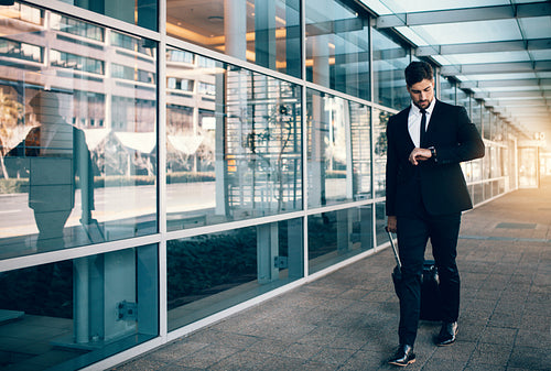 Business traveler walking in airport and looking at his watch