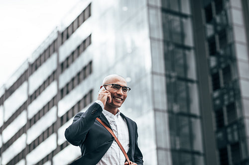 Businessman talking over mobile phone walking outdoors