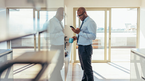 Businessman checking mobile phone while having breakfast