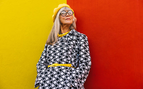 Senior woman looking away thoughtfully against a colourful wall