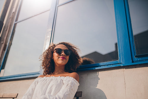 Happy female wearing sunglasses sitting outside