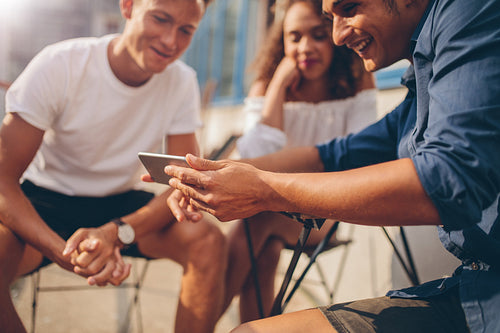 Young people sitting outdoors and looking at mobile phone