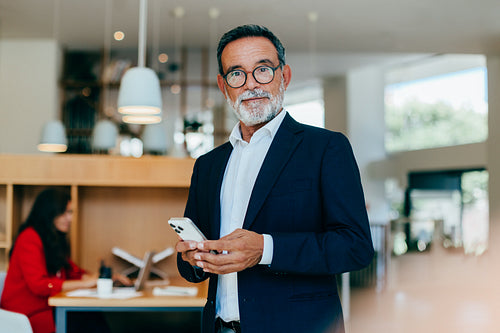 Senior executive holding a phone in a bright office environment