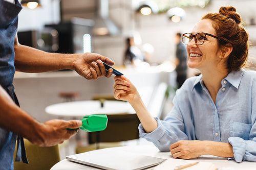 Woman using a credit card to pay for her bill in a coffee shop