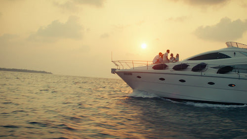 Golden sunset illuminates friends on a luxury yacht cruising peacefully on the ocean