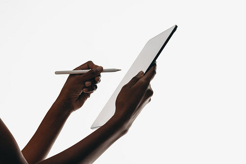 Person using a digital tablet with a stylus for creative work