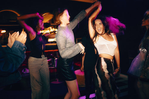 Friends dancing joyfully together at a nightclub during an evening celebration