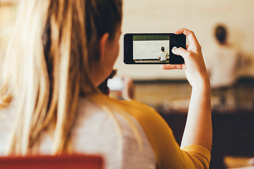 Girl recording important lecture by a teacher in classroom