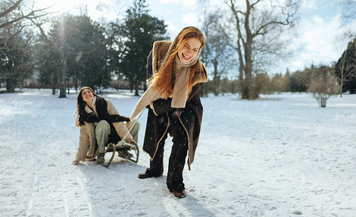 Laughing woman pulls a wooden sled across snow