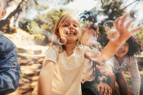 Girl with friends catching the soap bubbles