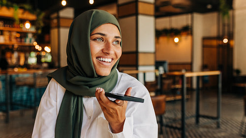 Businesswoman with a headscarf speaking on the phone in a cafe