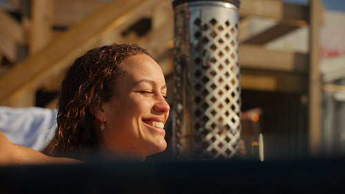 With sunlight on the water, the woman lingers in a quiet hot tub retreat