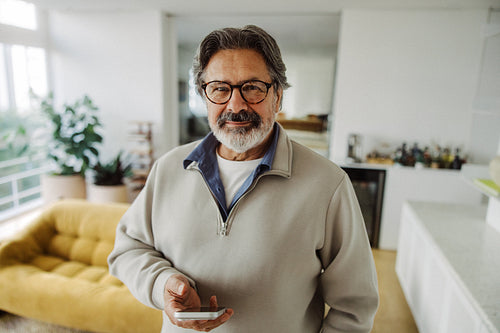 Senior man holds a smartphone at home