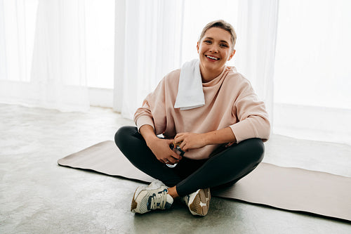 Woman on yoga mat resting after fitness exercise with water during post workout recovery