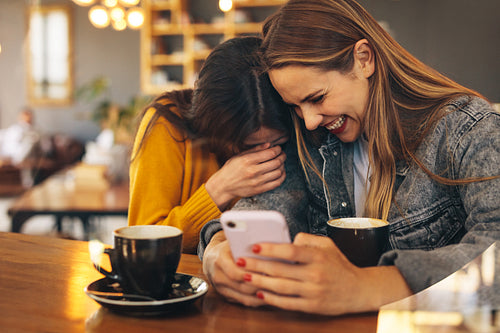 Two women sitting at coffee shop having fun