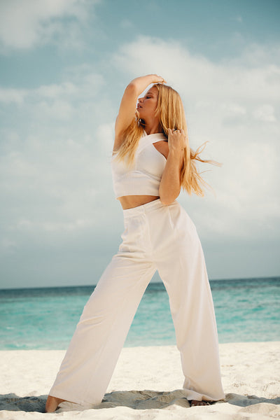 Young woman posing confidently on a sunny beach with serene ocean views