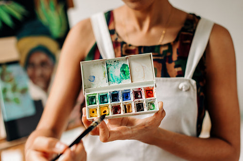 Unrecognizable young painter holding a palette in her studio