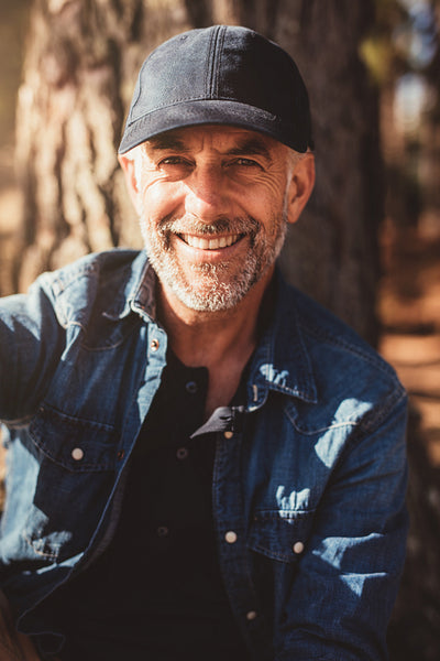 Senior man sitting by a tree on summer day