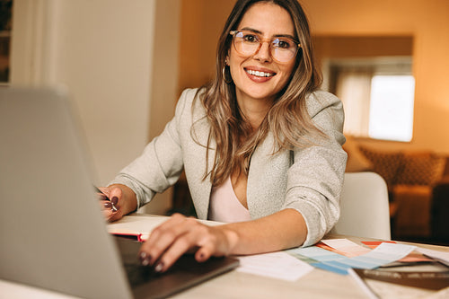 Happy female designer working in her home office
