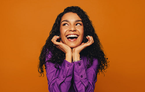 Cheerful woman with curly hair on vibrant coloured background