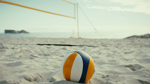 Handheld shot of beach volleyball net and ball on empty beach