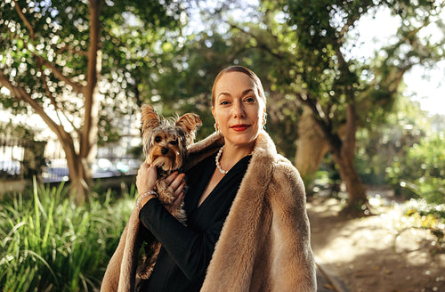 High class woman holding her puppy outdoors
