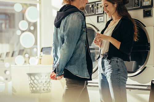 Smiling couple listening to music standing in a laundry room