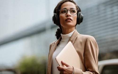 Businesswoman with headphones walking down the street