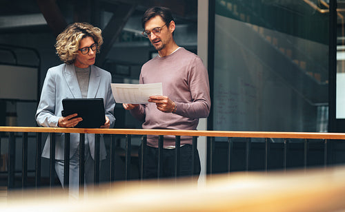 Business people reading a document together. Two professionals analyse a financial report in an office