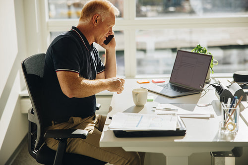 Senior businessman talking over mobile phone at work
