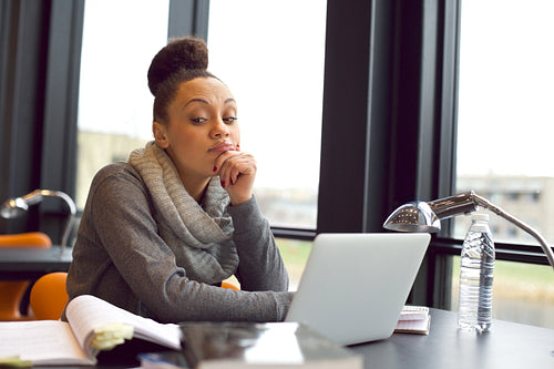 Young woman getting bored while studying in library