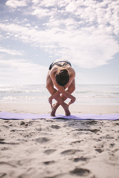 Sports woman doing yoga along the beach