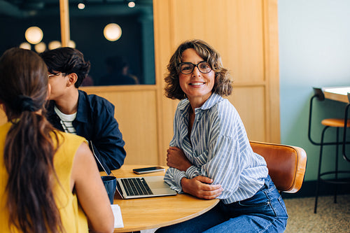 Smiling woman in casual attire at table with colleagues in meeting