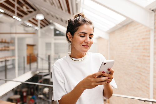 Self-employed businesswoman using a smartphone in a warehouse