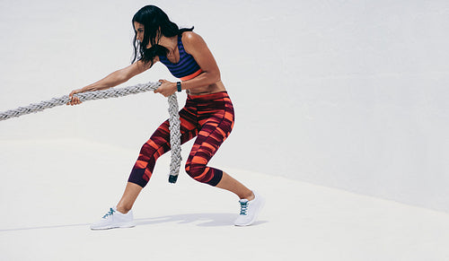 Fitness woman doing workout using a battle rope