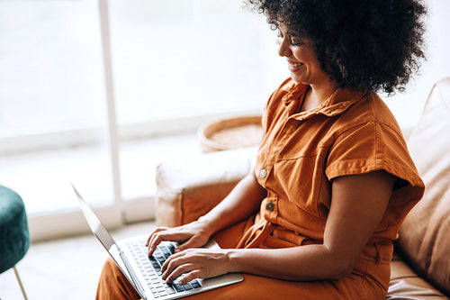 Happy young businesswoman typing on a laptop