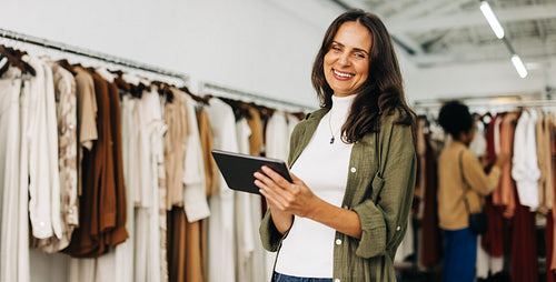 Happy clothing store owner using a tablet to manage her small business