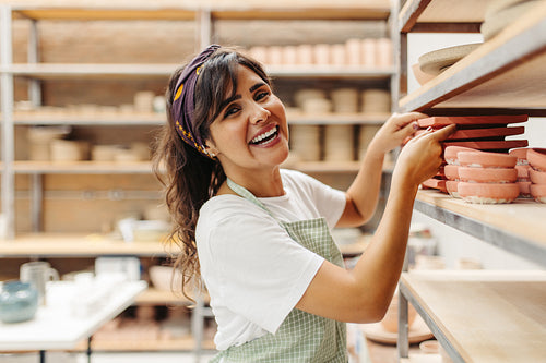 Young craftswoman smiling at the camera in her ceramic shop