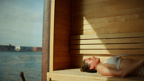 Wellness in the sauna with a woman resting by the waterfront