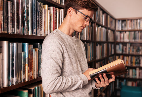 Young university student reading a book in library